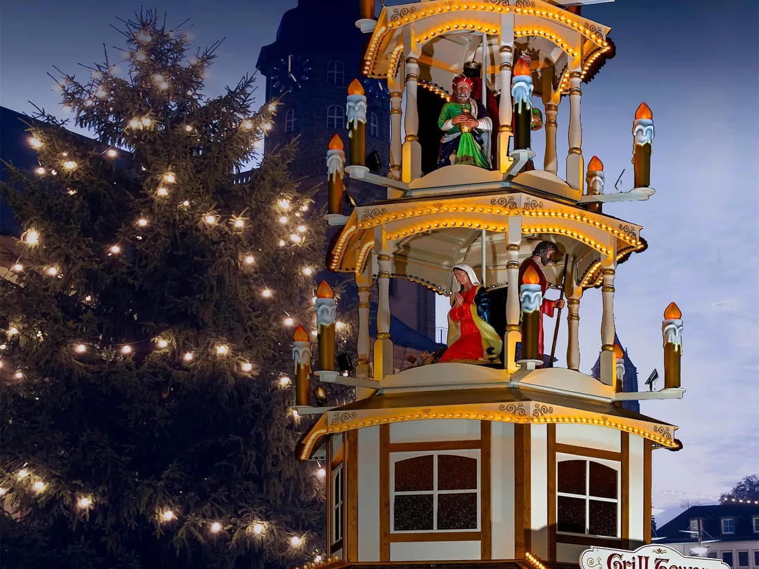 Weihnachtspyramide zur blauen Stunde neben einem geschmückten Baum
