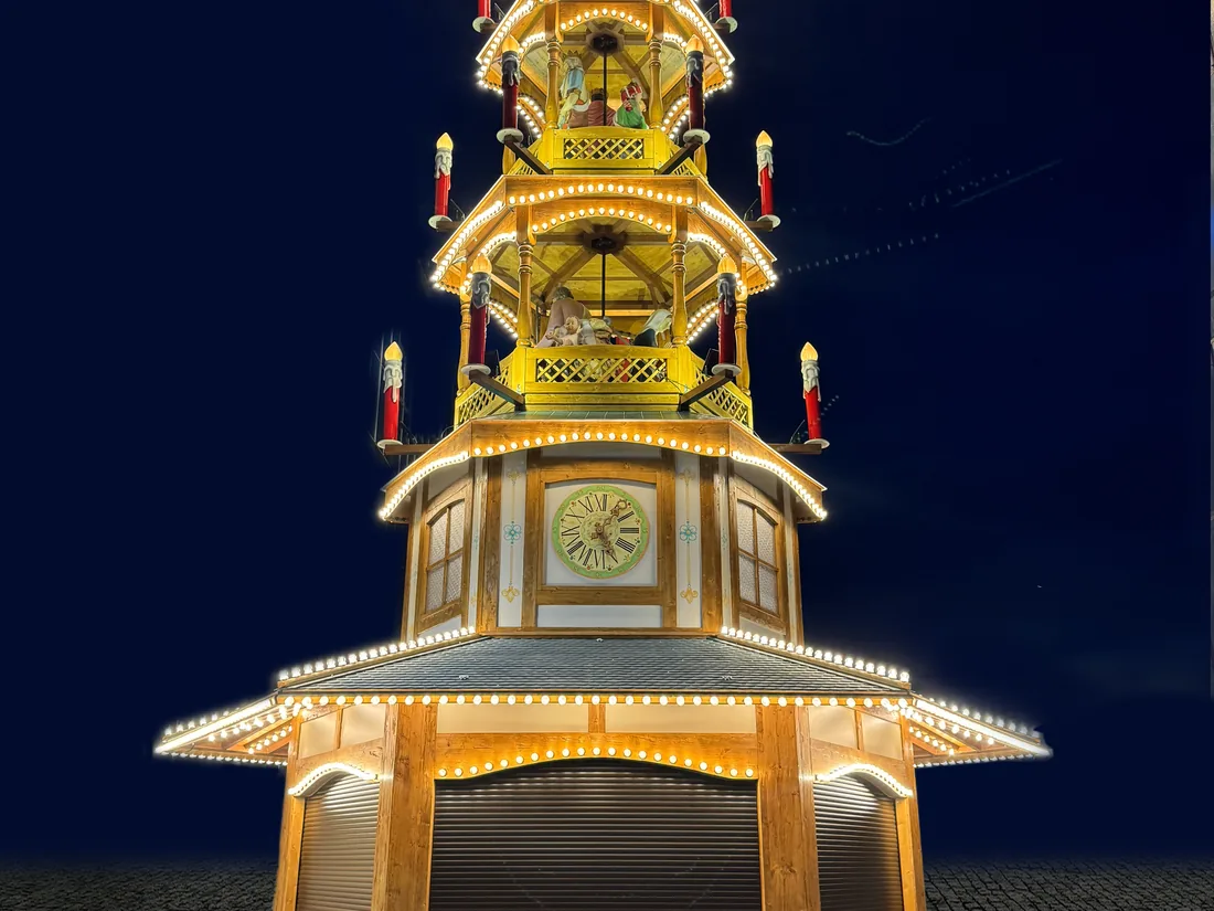 Weihnachtspyramide mit Uhr und beleuchteten Etagen vor blauem Abendhimmel