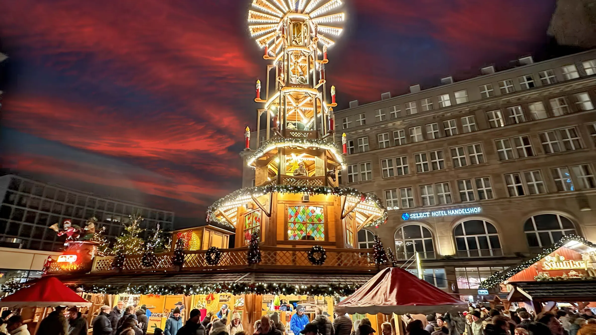 Große Weihnachtspyramide für den Außenbereich auf einem Weihnachtsmarkt, beleuchtet mit Publikum davor