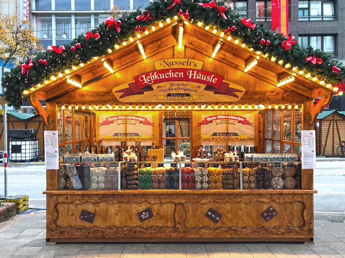 Weihnachtsmarktbude aus Holz im Betrieb, mit Ware auf der Theke und Kunden davor